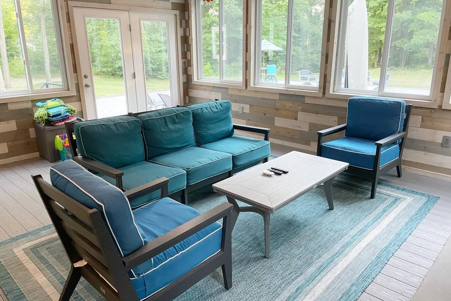 Sunroom seating with a blue sofa and chairs facing the trees