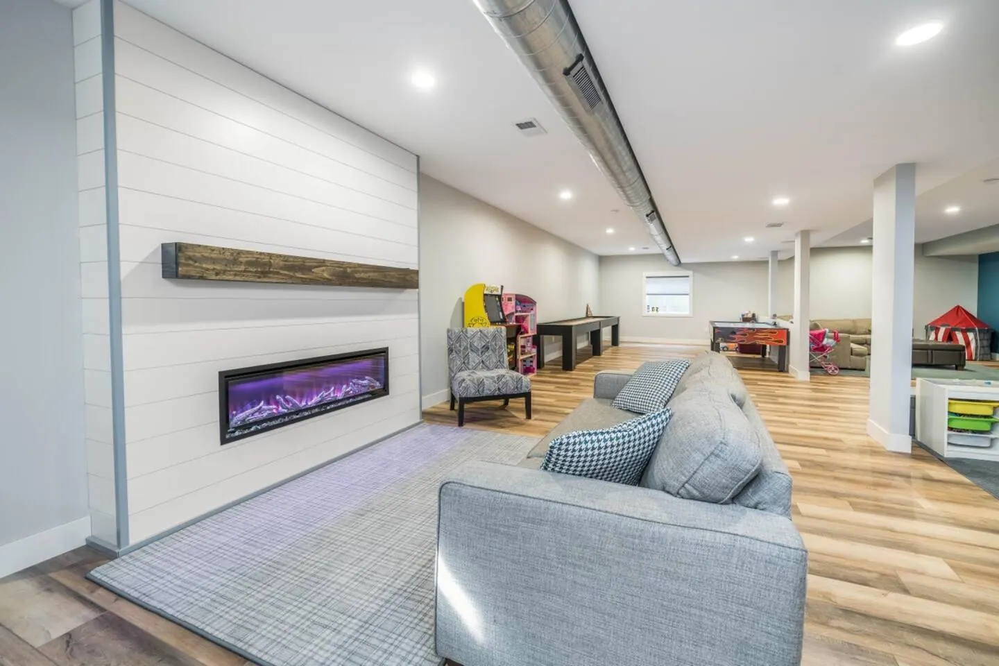 Basement lounge with a long sofa and a linear fireplace