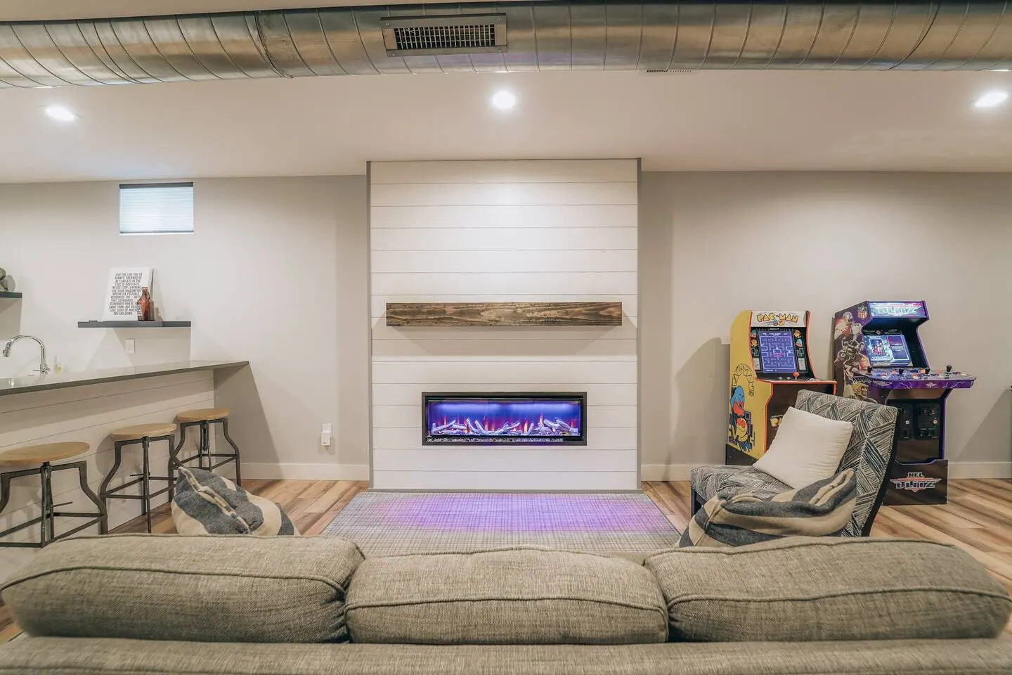 Game-level living area with fireplace, arcade, and shuffleboard beyond