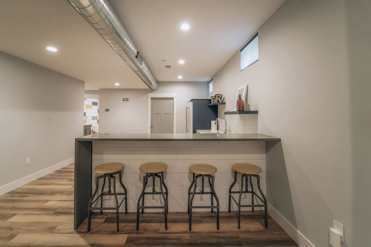 Basement bar with three stools and an open pass-through