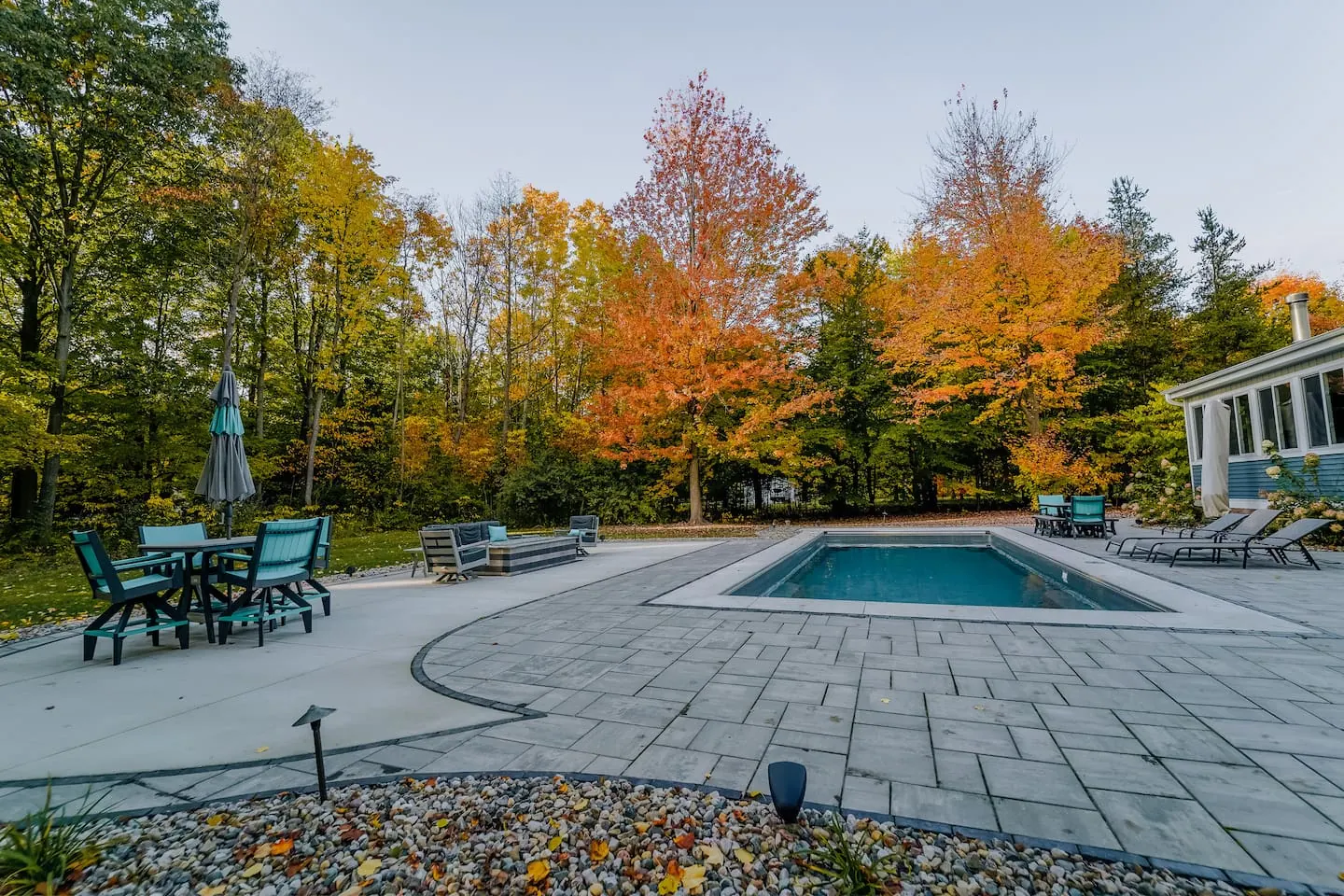 Wide autumn view of the pool and patio framed by trees